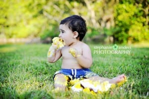 A baby eating cake in the grass.