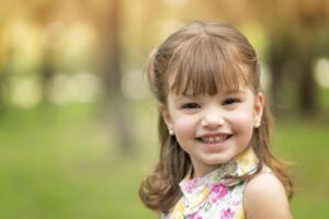 A little girl is smiling in a park.