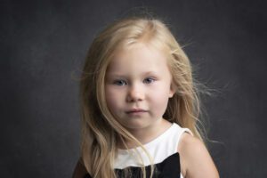 A little girl with long blonde hair is posing for a portrait.
