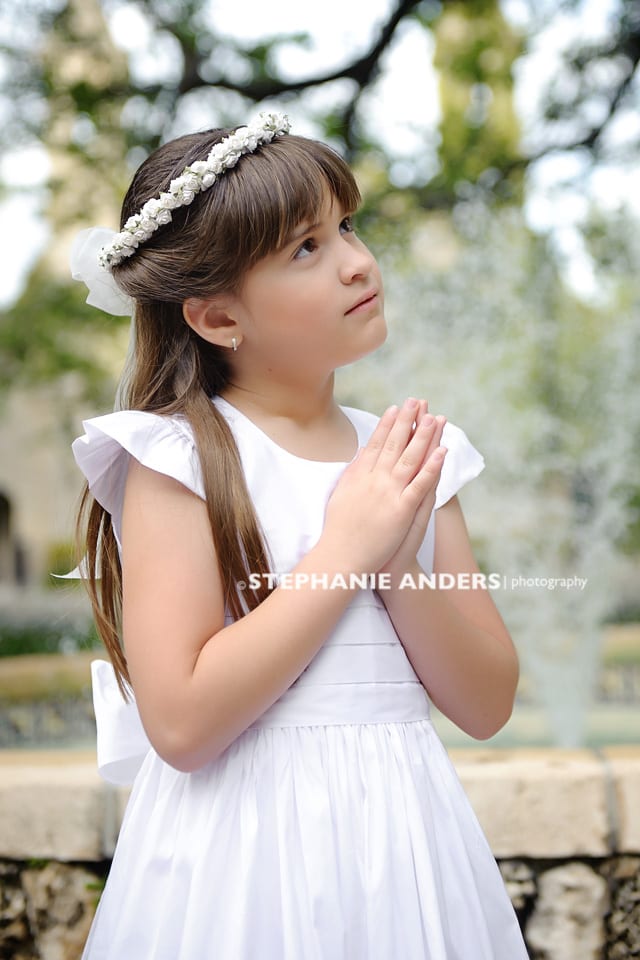 small girl in white dress looking to heaven and praying