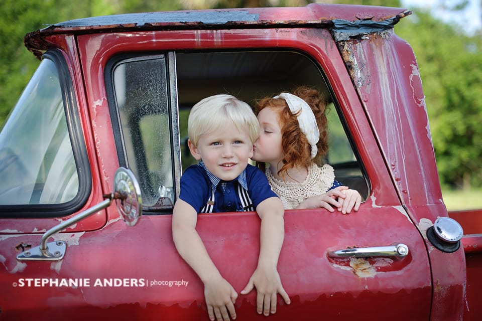 blonde boy and redhead girl in red truck 