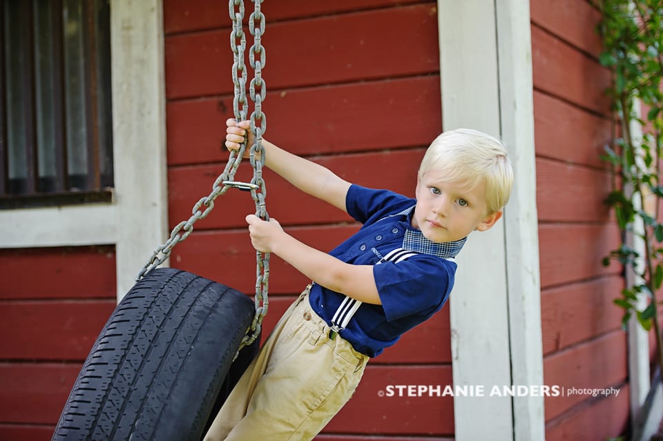 blonde boy haning on tire with blue shirt