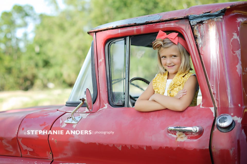 young girl in red truck with red bow in hair