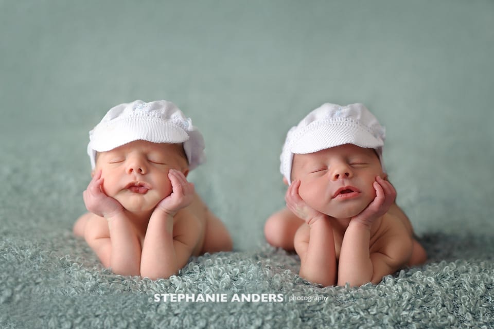 newborn twins with matching white hats