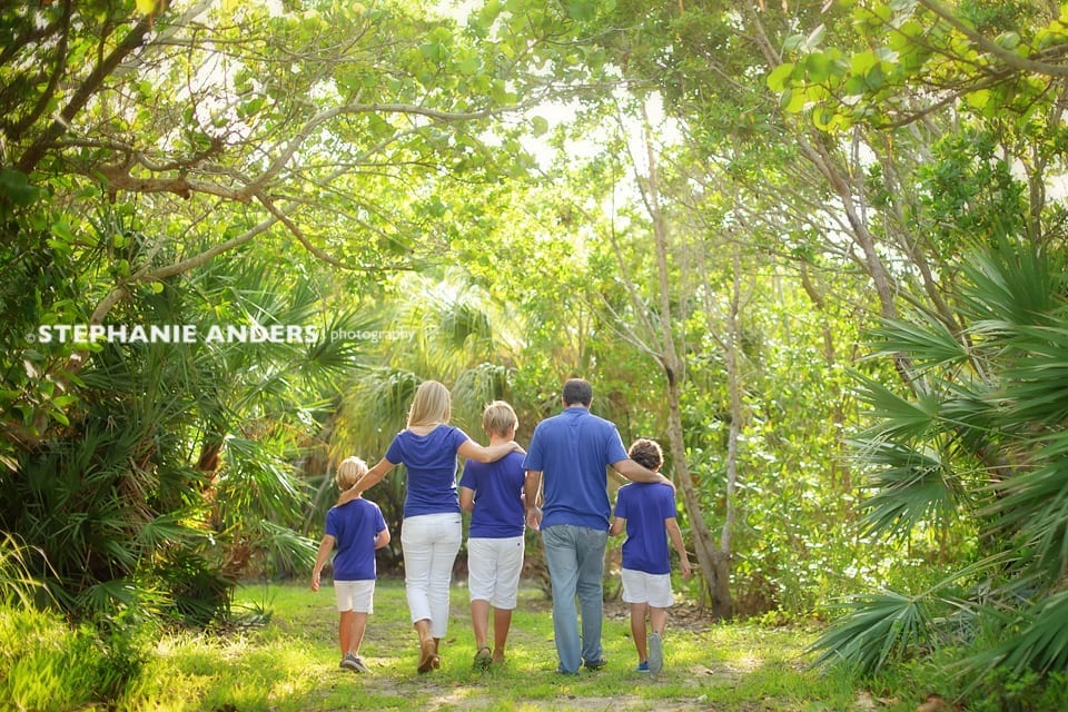 family dressed in blue walking through palm trees