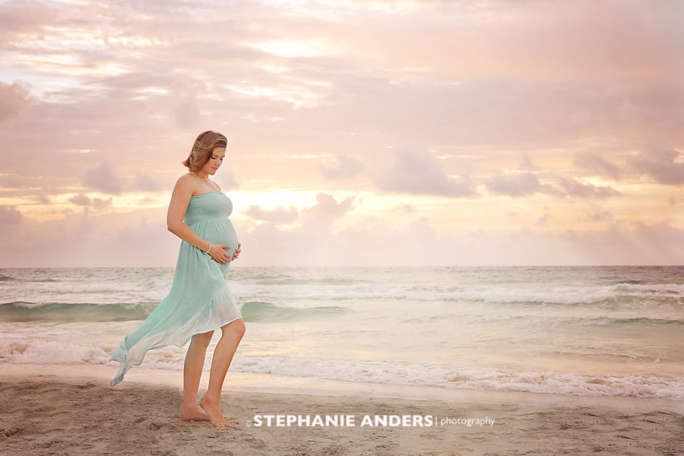 pink sunrise with pregnant woman waves on beach