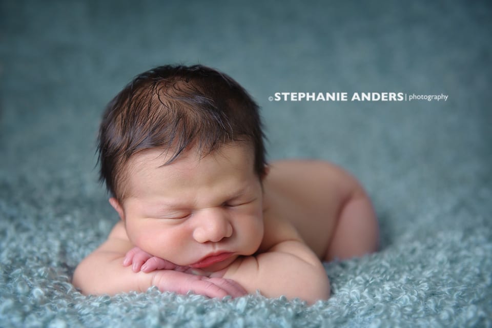 newborn baby with crossed arms on blue blanket