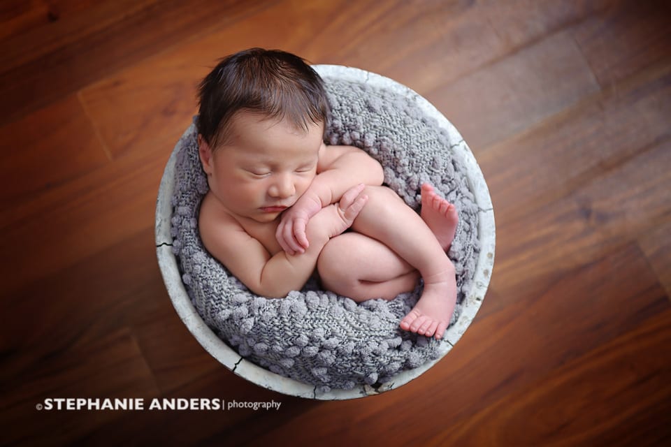 newborn in a basket on wood floor