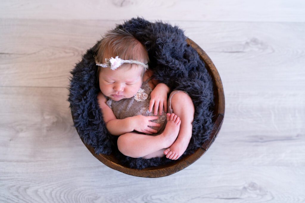 newborn girl in wooden bowl