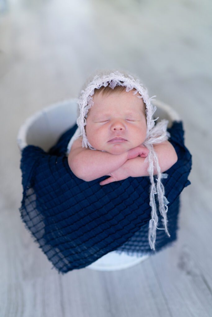 newborn girl with hat in bucket