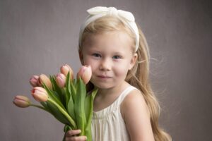 A little girl holding a bouquet of tulips in a childhood portrait.