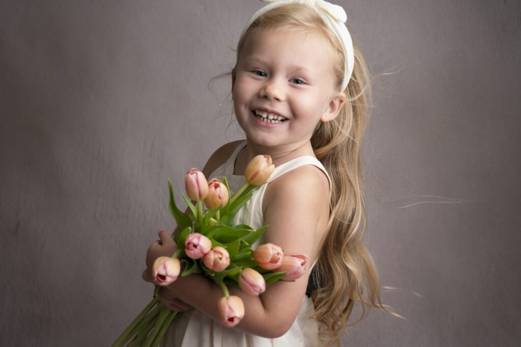 A little girl posing for photos with a bouquet of tulips.