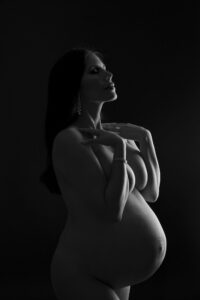 A pregnant woman posing in a black and white photo.