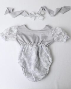 A grey and white baby romper and headband.