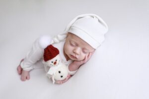 A baby sleeping with a stuffed snowman.