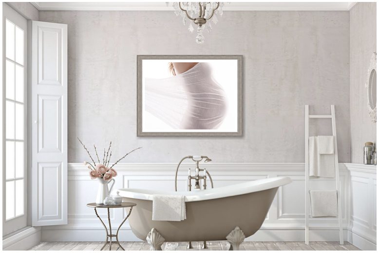 A white bathroom with a bathtub and a framed picture.