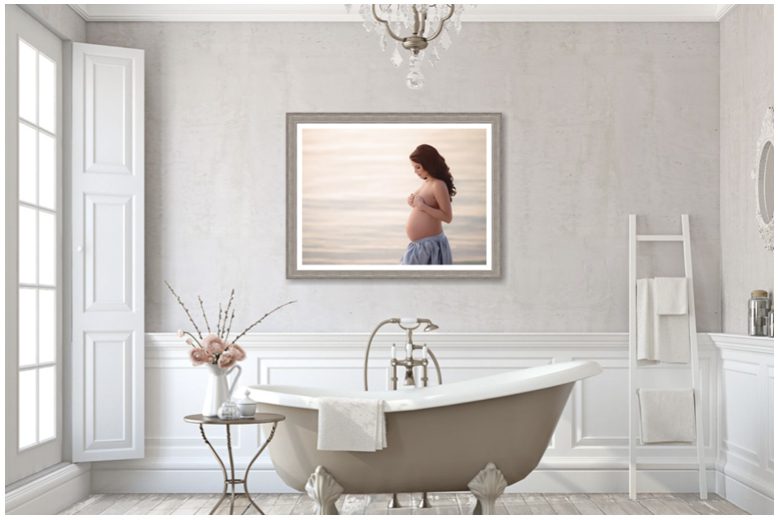 A framed photo of a pregnant woman in a bathroom.