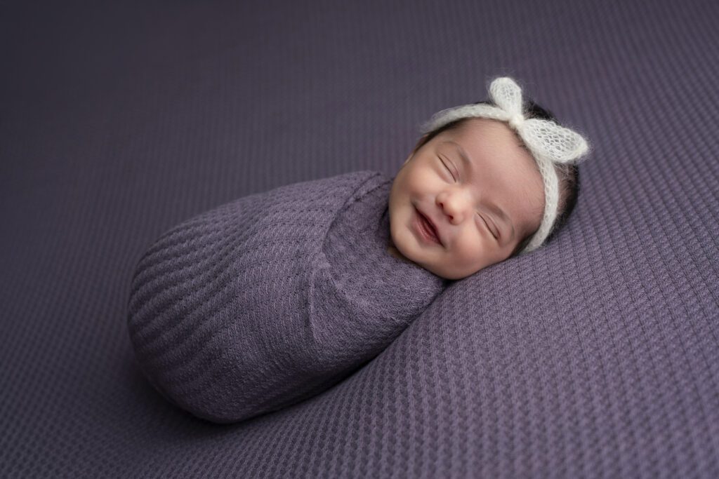 Newborn baby photographed in a soft neutral studio setup in Miami.
