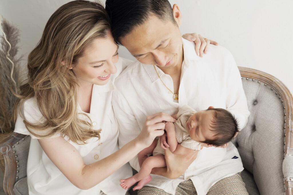 New parents holding their baby during a calm Miami newborn photography session.