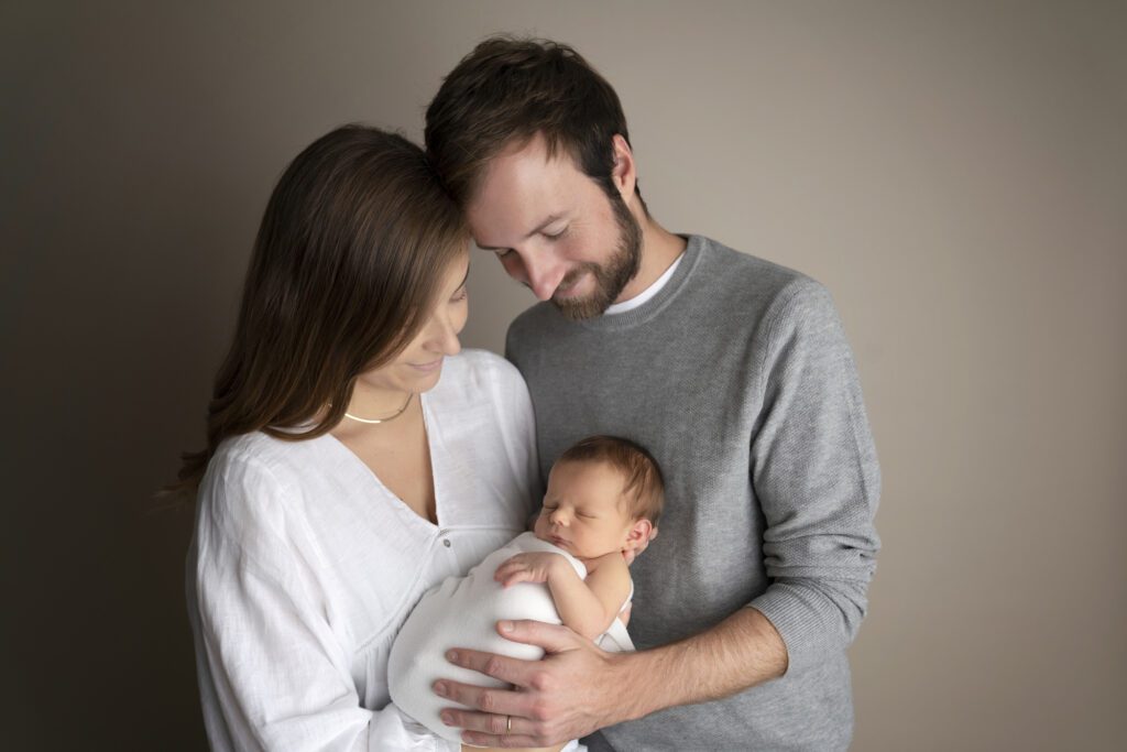 New parents holding their newborn baby during a timeless Miami newborn photography session.